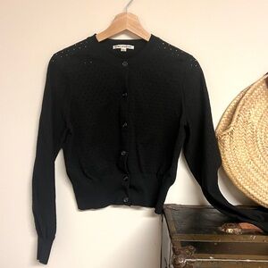 Acne Studios perforated black cardigan with clear buttons.